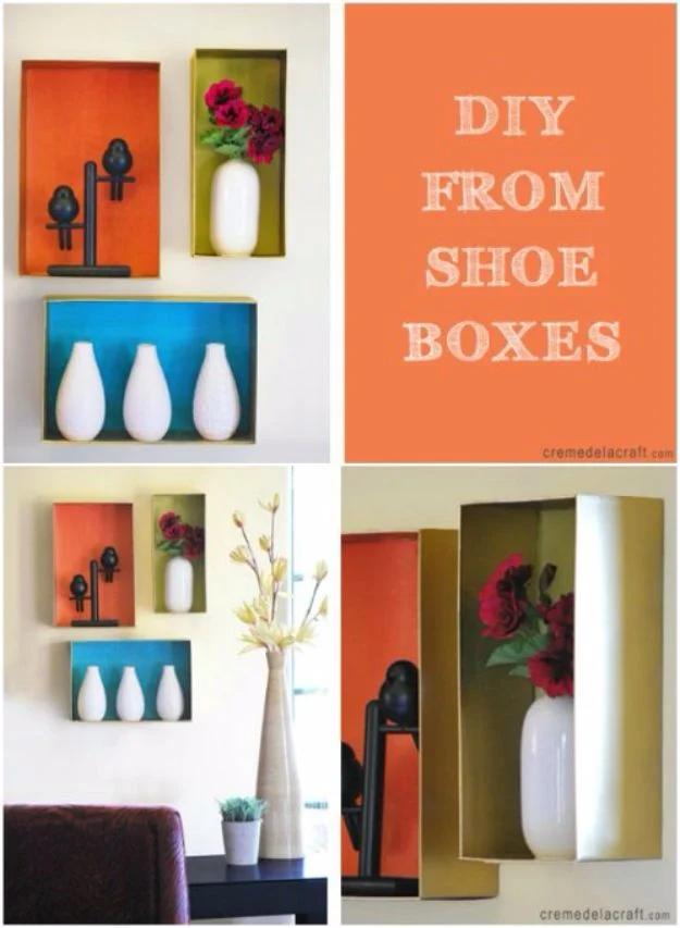 Shoe boxes mounted as wall shelves in orange, blue and gold holding white vases, titled DIY from shoe boxes