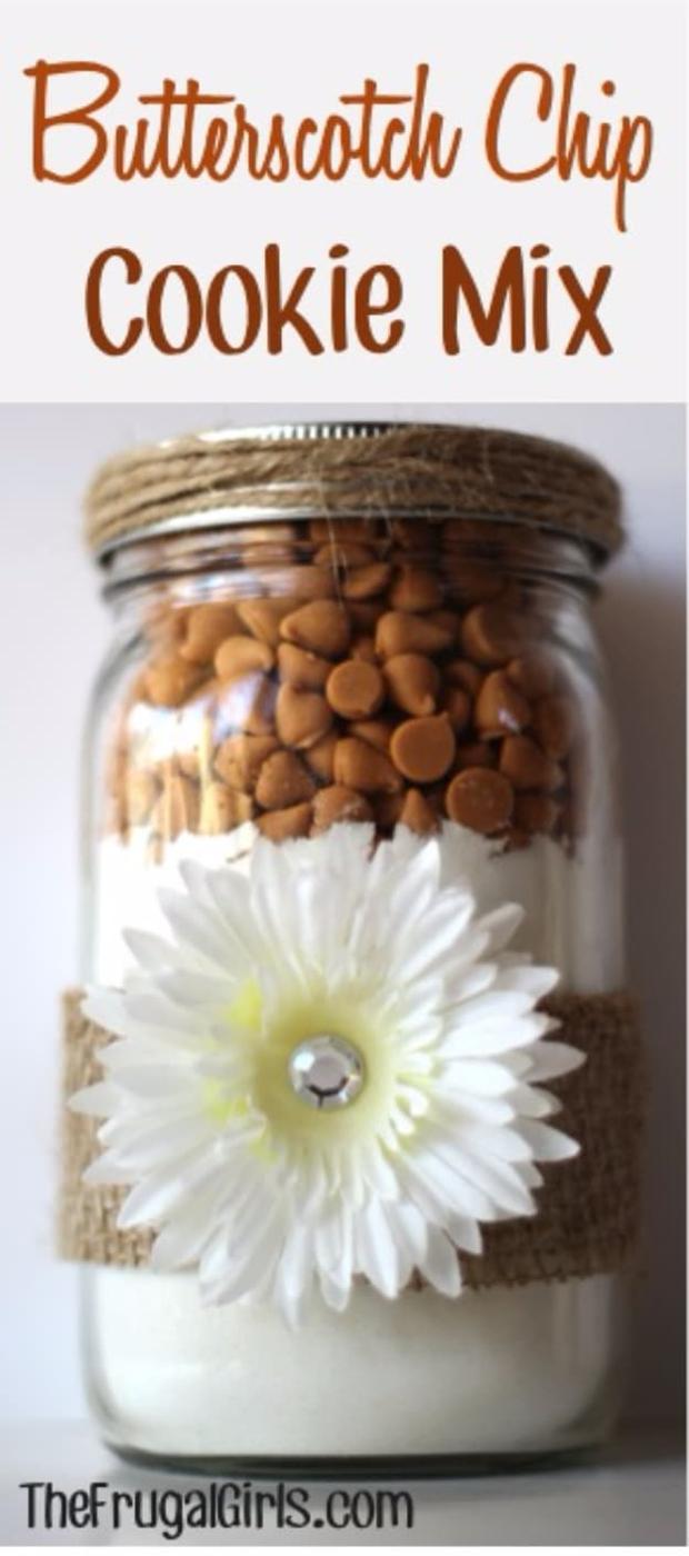 Wide mouth jar of butterscotch chip cookie mix layered over pale cake mix with a white daisy on front