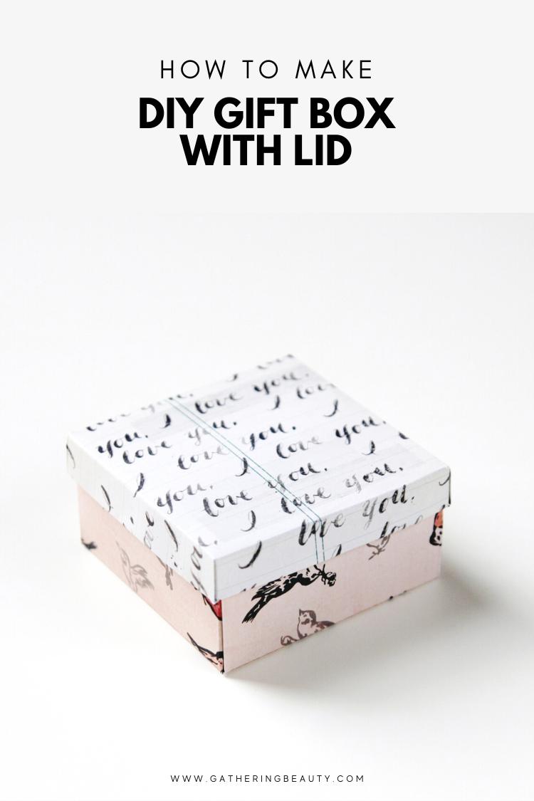 A small square gift box with a lidded top in pink and white patterned paper tied with fine green thread