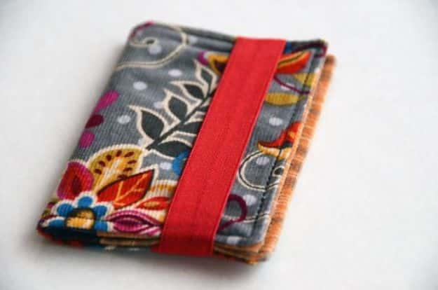 Business card wallet with elastic closure, a gray floral card wallet held shut by a red elastic strip