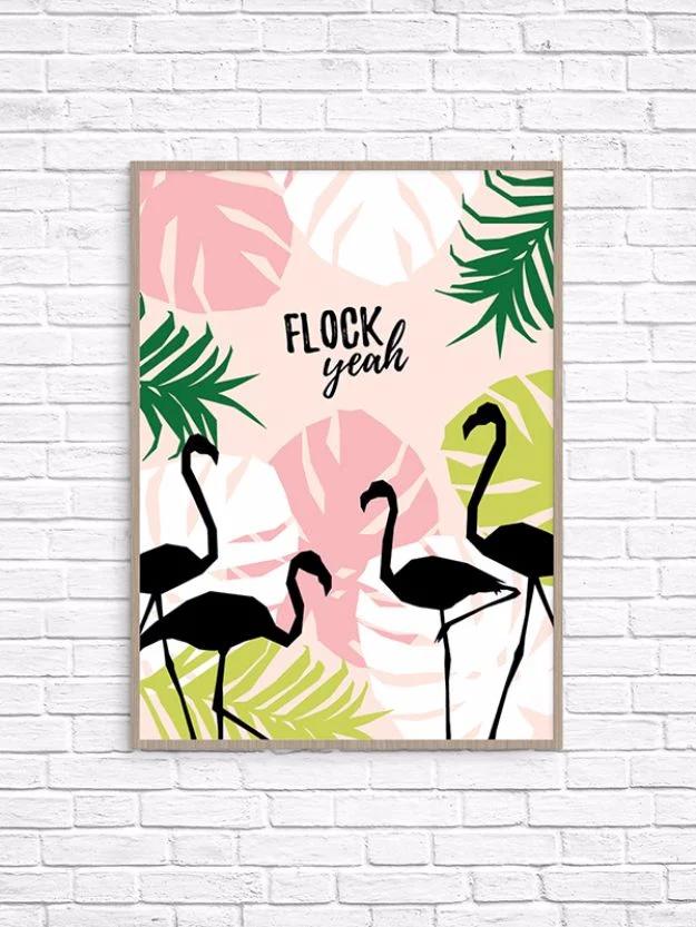 Flock yeah printable wall art, three black flamingo silhouettes among pink and green tropical leaves in a pale wood frame