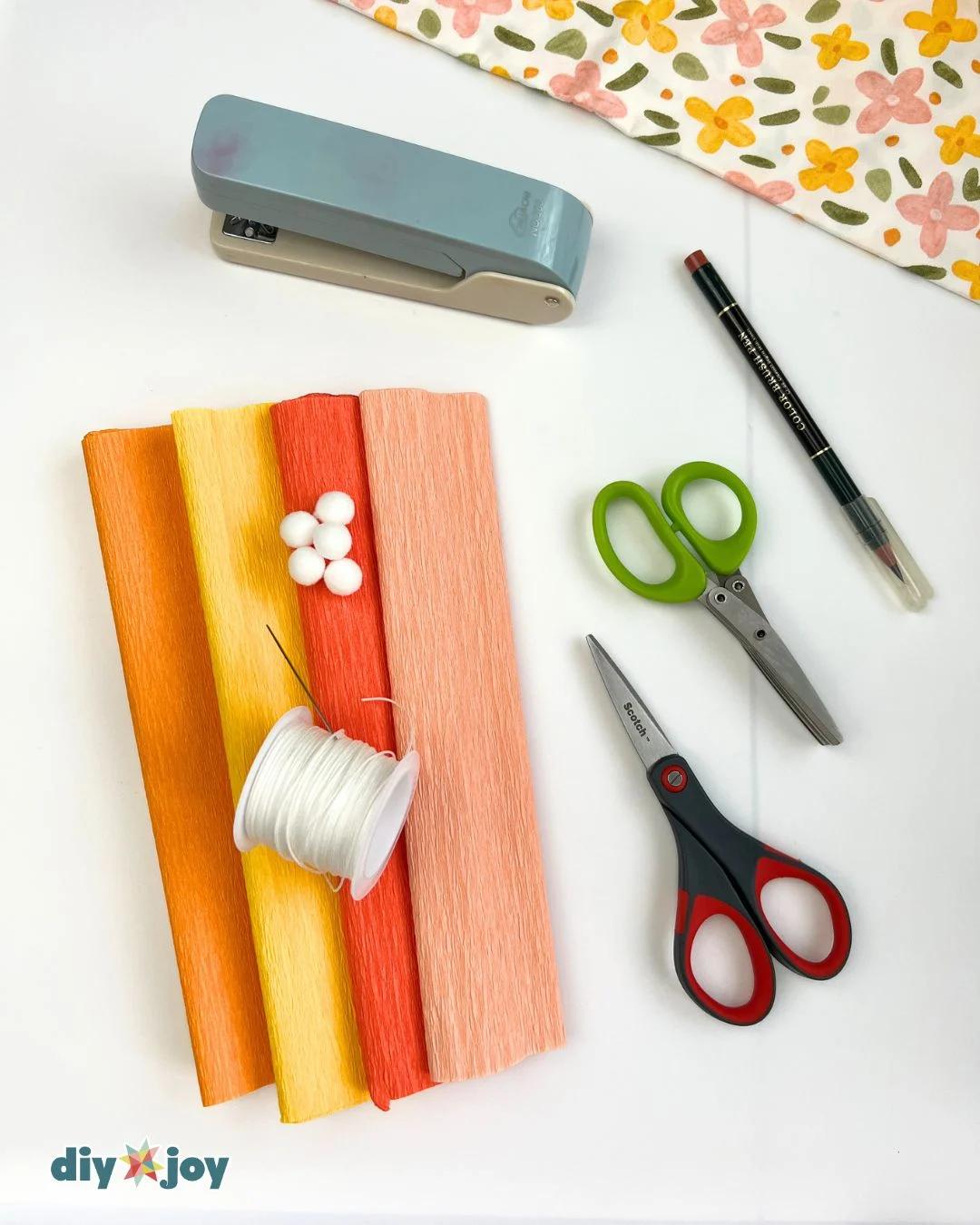 Craft Supplies Needed - crepe paper, scissors, thread, and pom-poms for marigold flowers