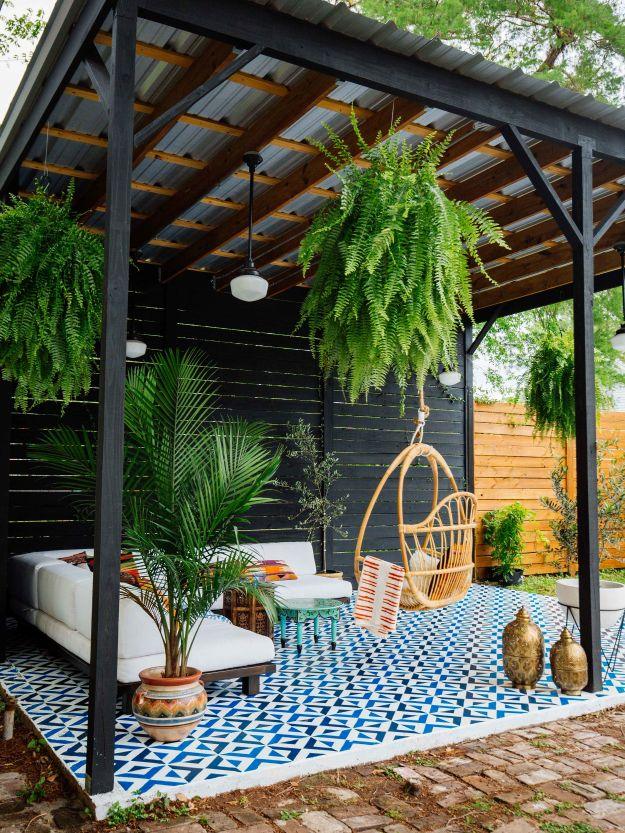 Painted floor tiles, a covered patio with a blue and white stenciled concrete floor, hanging chair and ferns