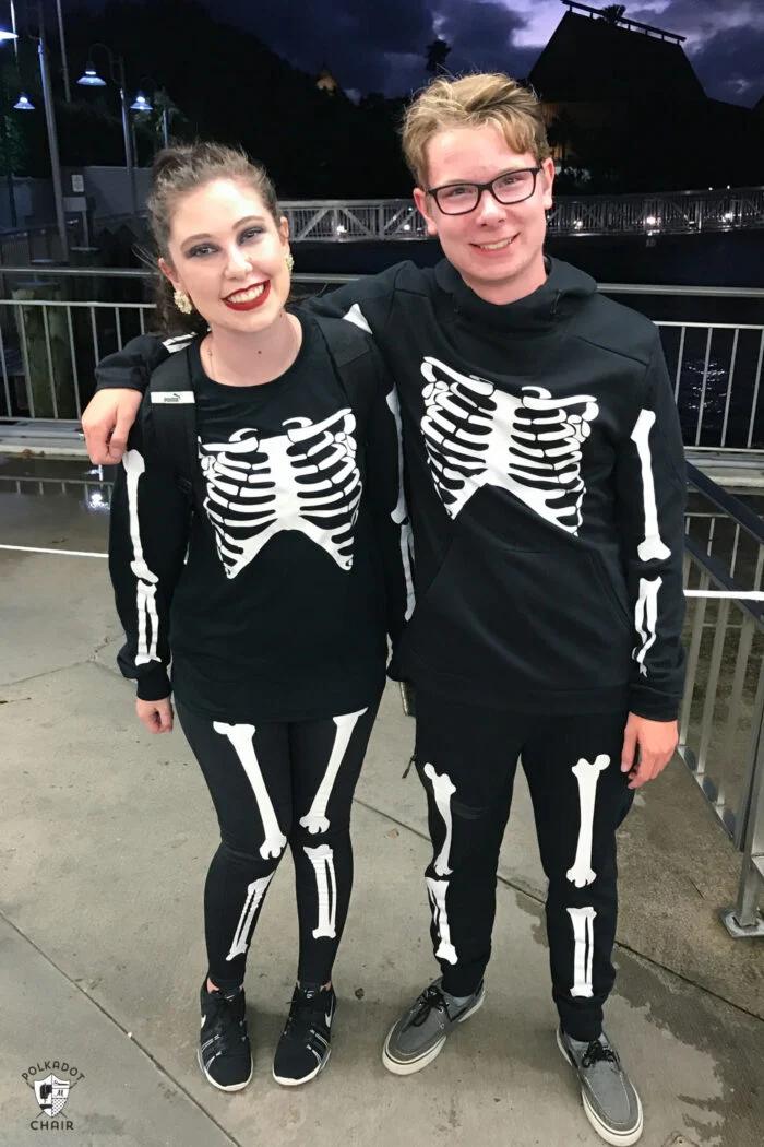 Two teens wearing black skeleton costumes with white iron-on bones outdoors and Polka Dot Chair source mark