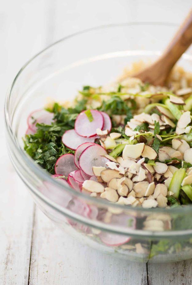 Shaved asparagus spring salad in a glass bowl with asparagus ribbons, sliced radish, almonds and couscous