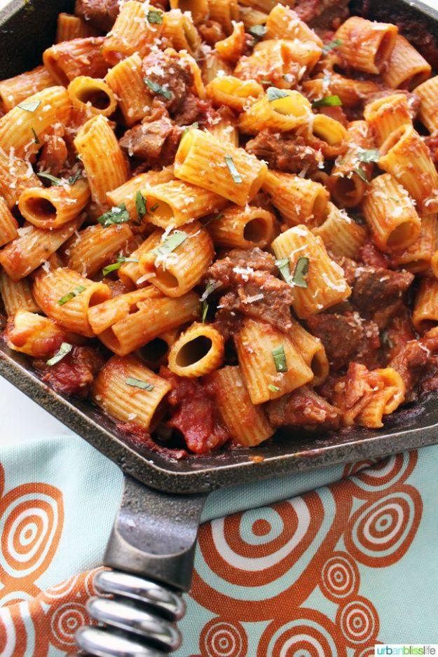 Italian sausage rigatoni in a skillet with a thick tomato sauce, fresh parsley and grated parmesan cheese