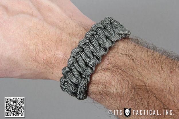 Gray quick release paracord bracelet worn on a wrist, woven so the cord unravels fast in an emergency