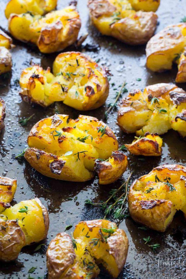 Sheet pan of smashed golden potatoes with torn crispy edges, olive oil and sprigs of fresh green thyme
