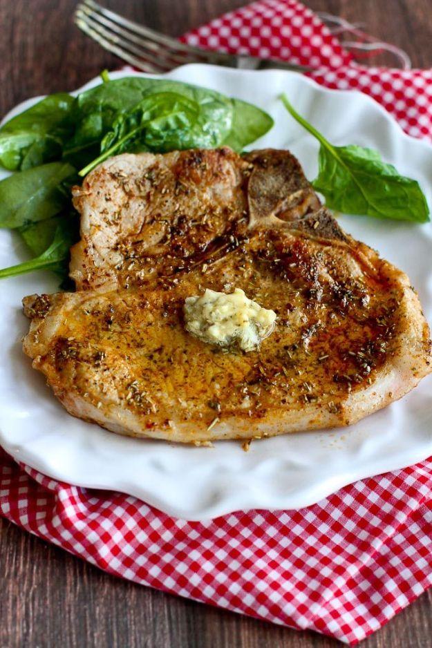 Thin cut herbed chop topped with a melting pat of garlic butter on a white plate over red gingham cloth