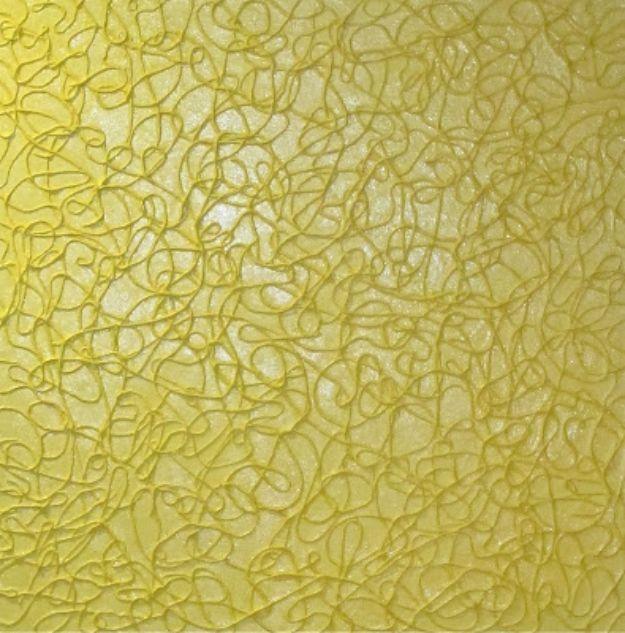 Close up of textured wall art made from looped string glued to a canvas and painted in a single bright yellow tone