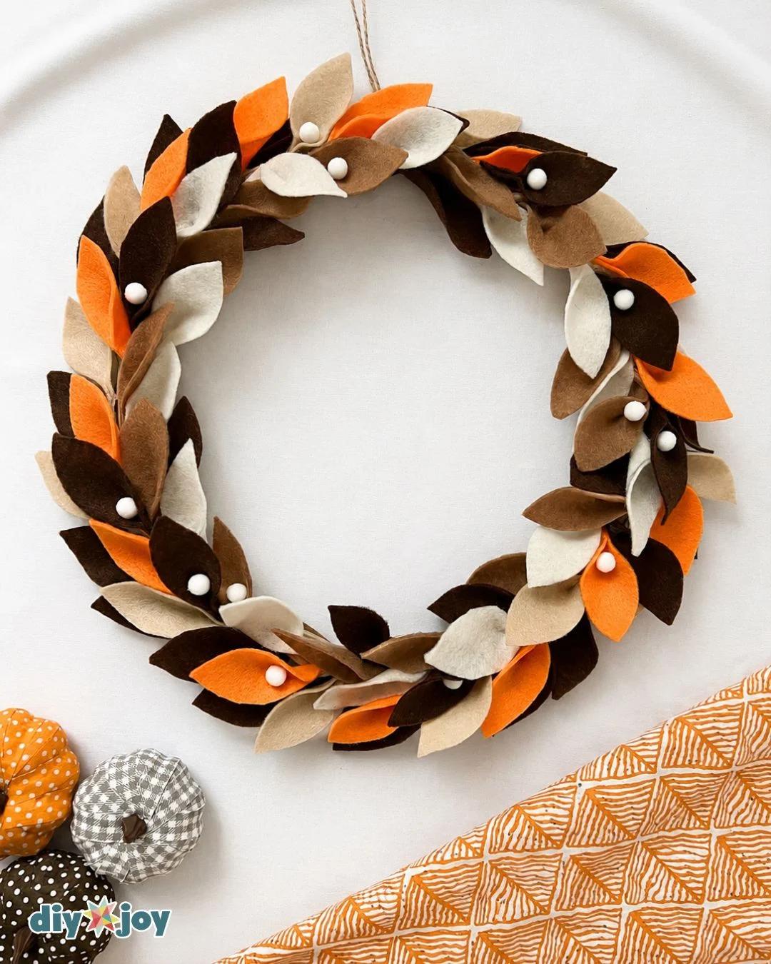 Easy DIY fall wreath tutorial: a colorful pumpkin wreath with layered felt leaves and small pom-poms for your front door.