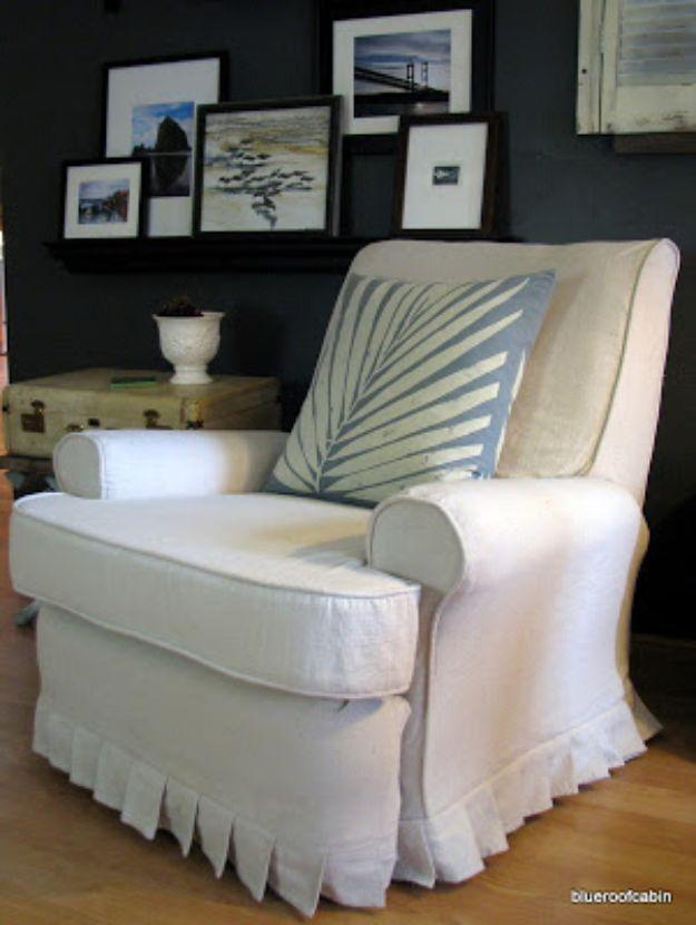Recliner covered in a natural drop cloth slipcover with a pleated skirt, against a dark wall of framed pictures