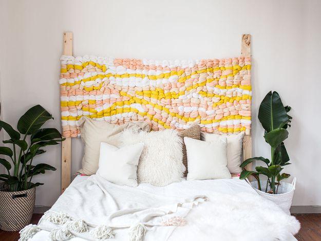 Woven headboard in cream, peach and yellow chunky wool, hanging above a white bed between two plants