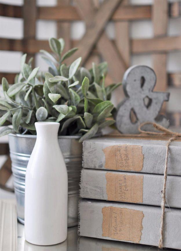 Three hardback books wrapped in plain linen and tied with twine sit stacked on a shelf beside a small vase