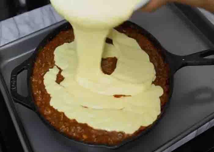 Pouring the cornbread batter over the chili