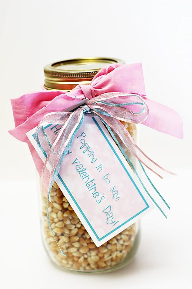 Mason jar layered with popcorn kernels and seasoning with a Valentine tag tied to the lid, an inexpensive DIY Valentine idea
