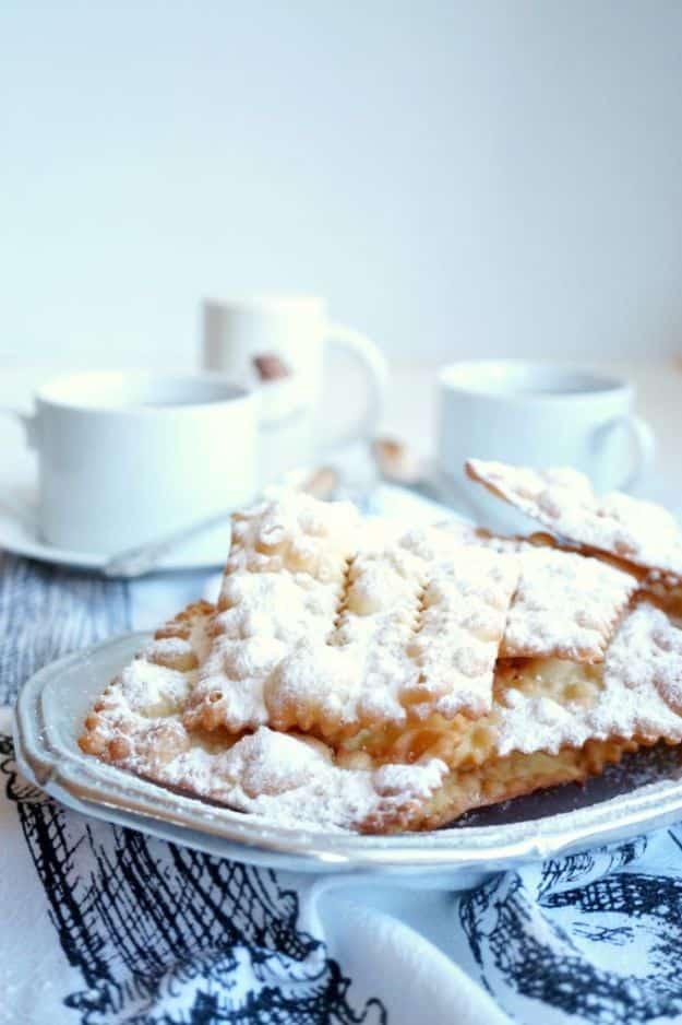 Chiacchiere fried Italian pastries, thin blistered strips of dough buried under a heap of powdered sugar