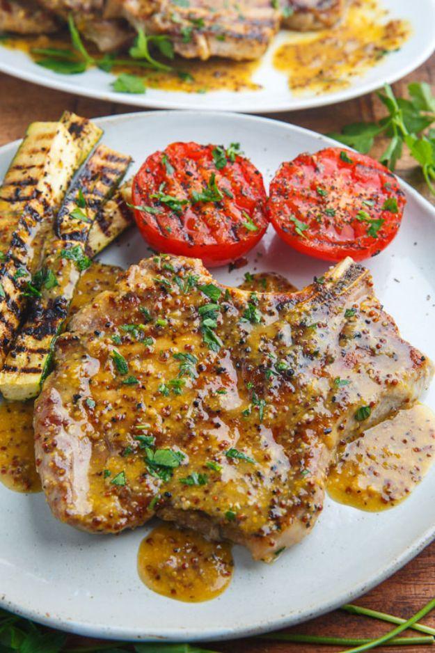 Honey mustard grilled pork chop with caramelized edges on a plate beside grilled tomato halves and zucchini