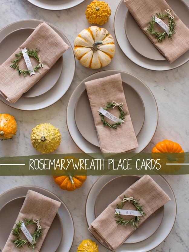 Rosemary wreath place cards with a bent rosemary sprig tied in ribbon holding a curled name tag at each plate