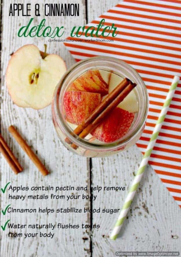 Apple cinnamon detox water in a mason jar with apple slices and a cinnamon stick beside a green paper straw