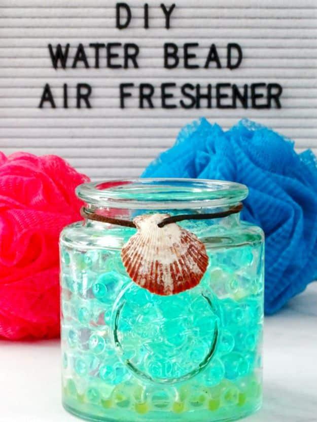 Mason jar of bright blue water beads with a shell tied at the rim, under a DIY water bead air freshener sign