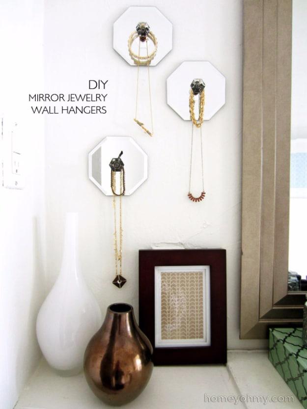 Mirror jewelry wall hangers, three octagonal mirrors with knobs holding necklaces on a wall above a shelf