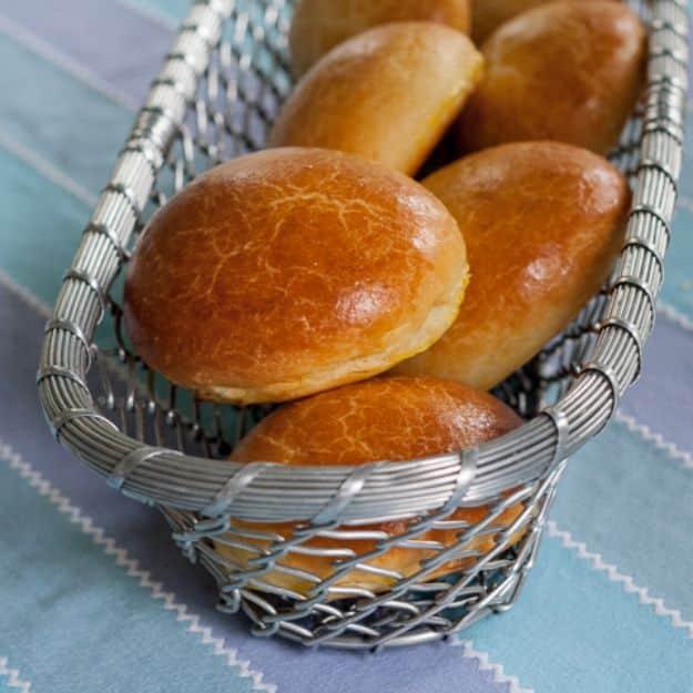 Brioche hamburger buns with deep golden egg washed tops cooling on a wire rack, soft and rich inside