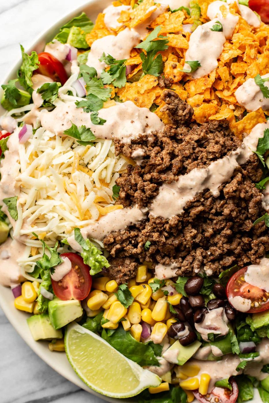 Easy beef taco salad with seasoned ground beef, cheese, corn, black beans and avocado over chopped romaine