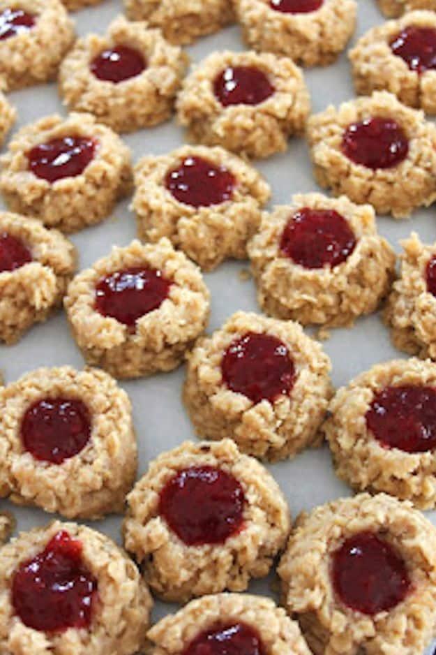 No bake PB and J cookies, neat rows of pale oat cookies each with a red jam filled thumbprint in the center