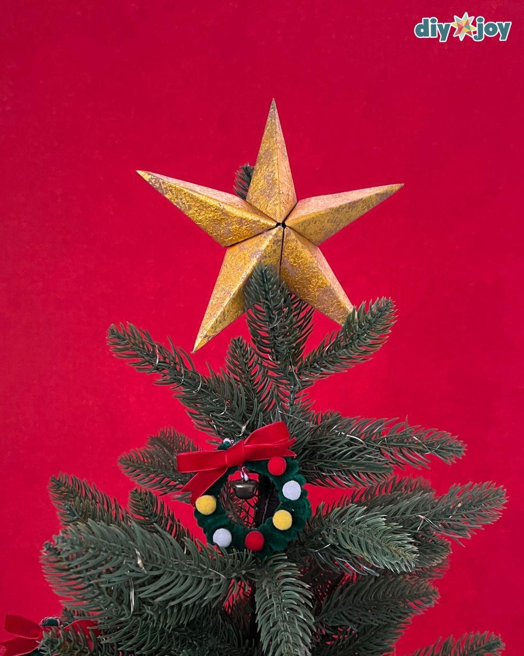 Paper bag star ornament used as a tree topper on a small tabletop Christmas tree display at home this season
