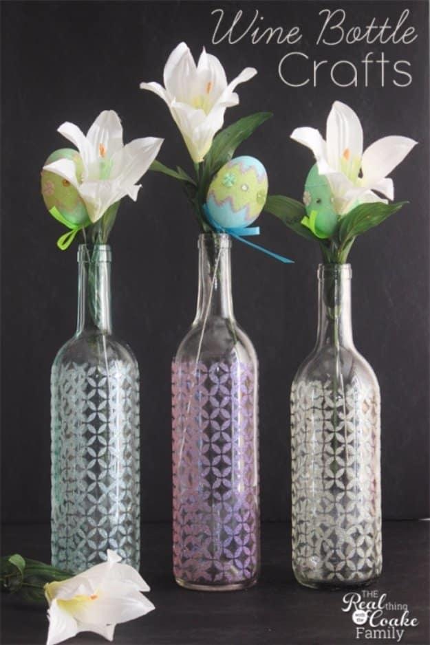 Stenciled wine bottle glitter vases, three bottles with pale stenciled patterns holding white lilies