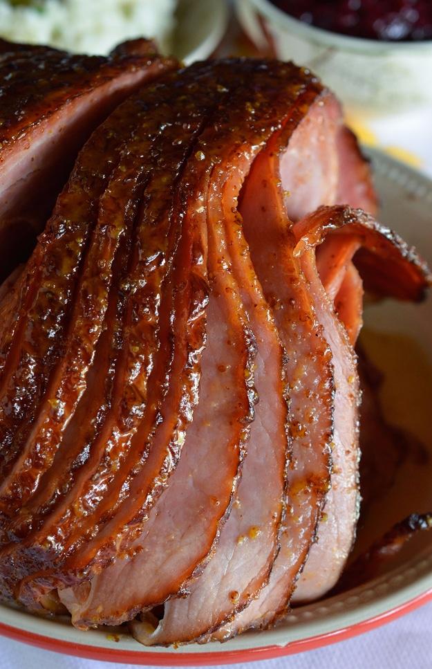 Pineapple honey glazed spiral ham sliced on a serving platter with a shiny golden glaze over the cut edges