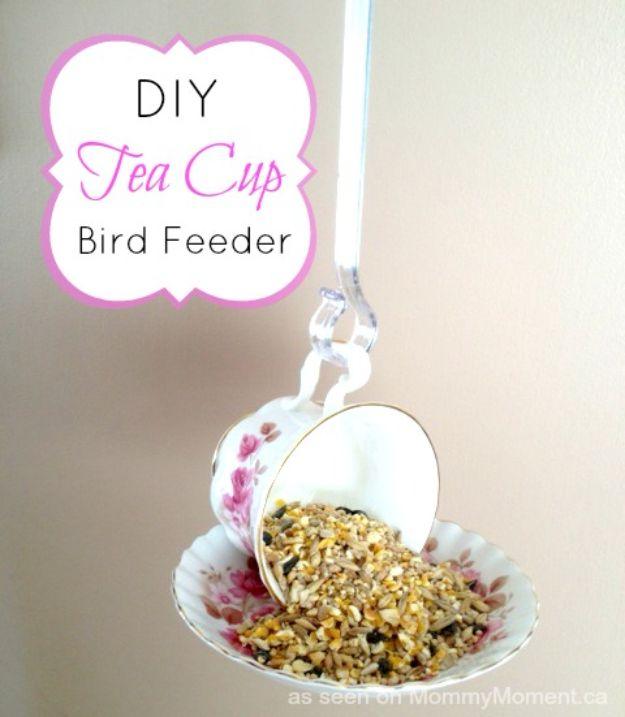 Floral teacup glued on its side to a matching saucer with birdseed spilling out, hanging from a clear plastic hook