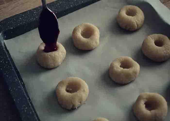 Adding fruit jam over the vegan cookies