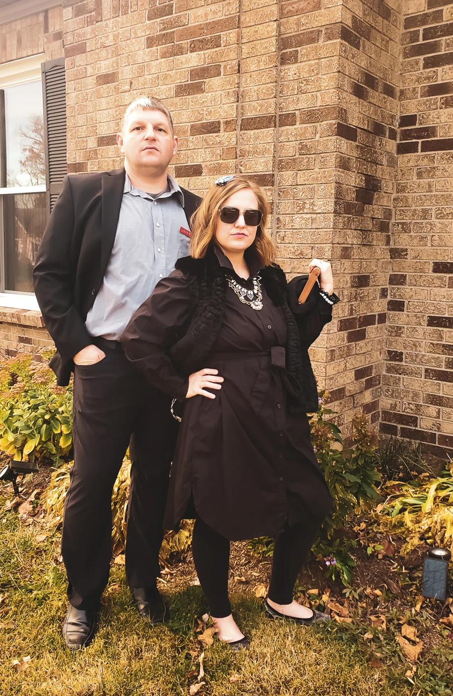 Johnny and Moira Rose couples costume with a black shirtdress, fur vest, dark sunglasses and a sharp black suit