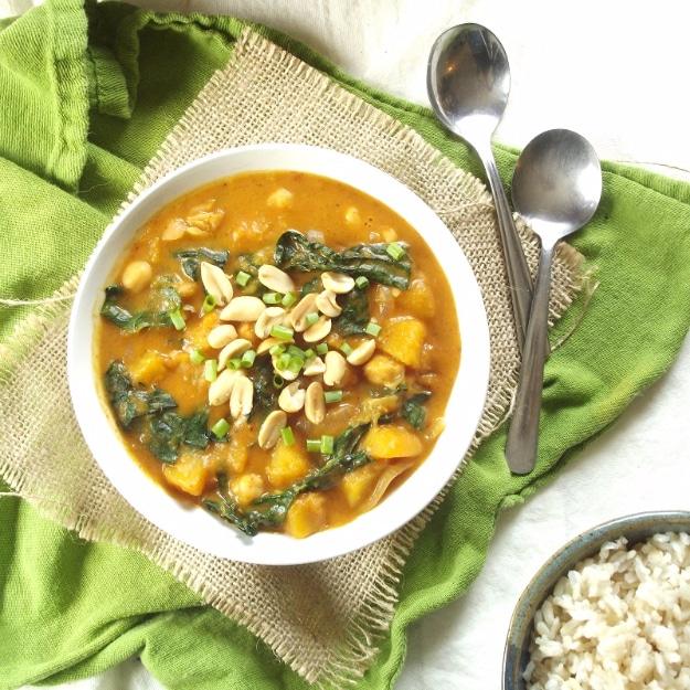 Butternut squash kale and chickpea massaman curry in a bowl with peanuts scattered over a green napkin