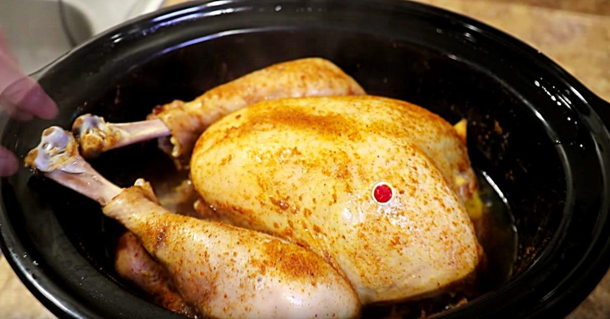 A whole turkey cooked in a crockpot, moist and golden, being lifted from the slow cooker onto a platter