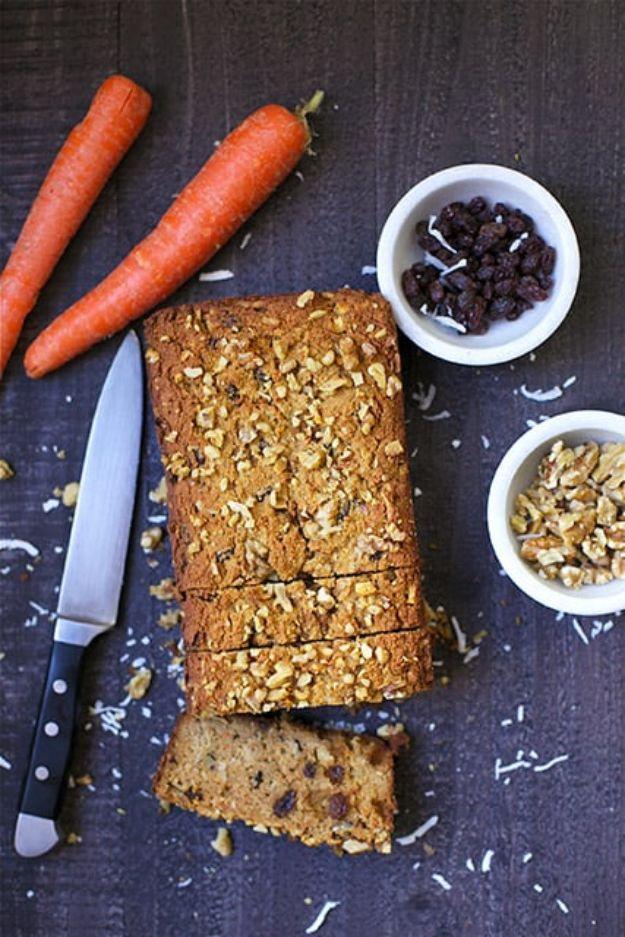 Paleo morning glory bread sliced on a dark board with carrots, raisins and walnuts in bowls beside it
