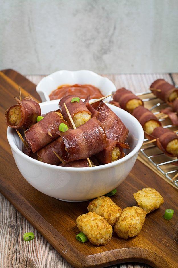 Bacon wrapped tater tots held with toothpicks, piled in a white bowl with barbecue sauce and loose tater tots