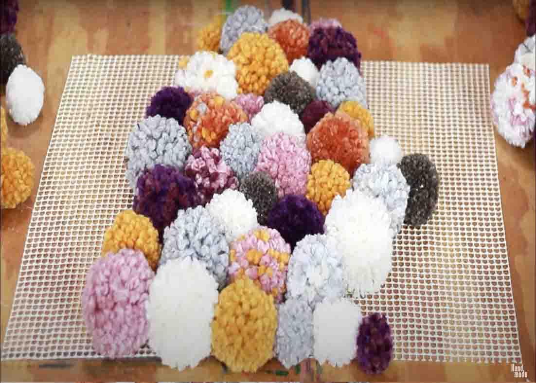 Placing the poms to the mat to make the rug