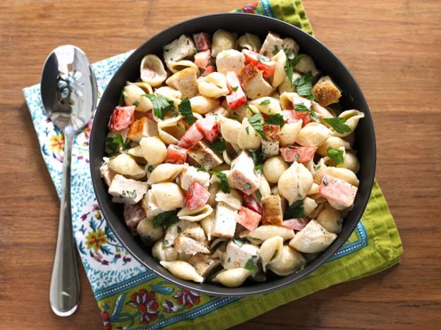Grilled chicken ranch pasta salad with medium shells, diced tomato and chopped flat leaf parsley in a bowl