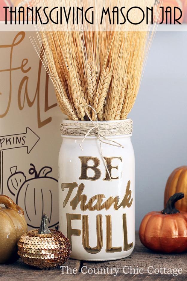 DIY Thanksgiving decor mason jar vase spray painted with a stenciled word outlined in gold and filled with wheat
