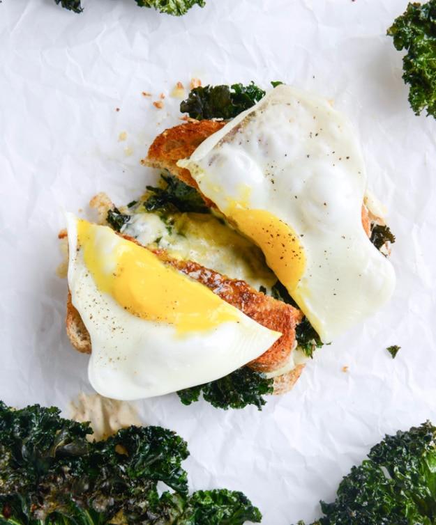 Crispy kale grilled cheese with fried eggs on top, runny yolks over melted cheese and roasted kale leaves