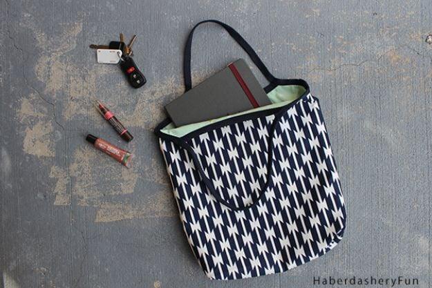 A reversible cotton tote folded to show both sides, a striped outer and a floral lining, on a park bench.