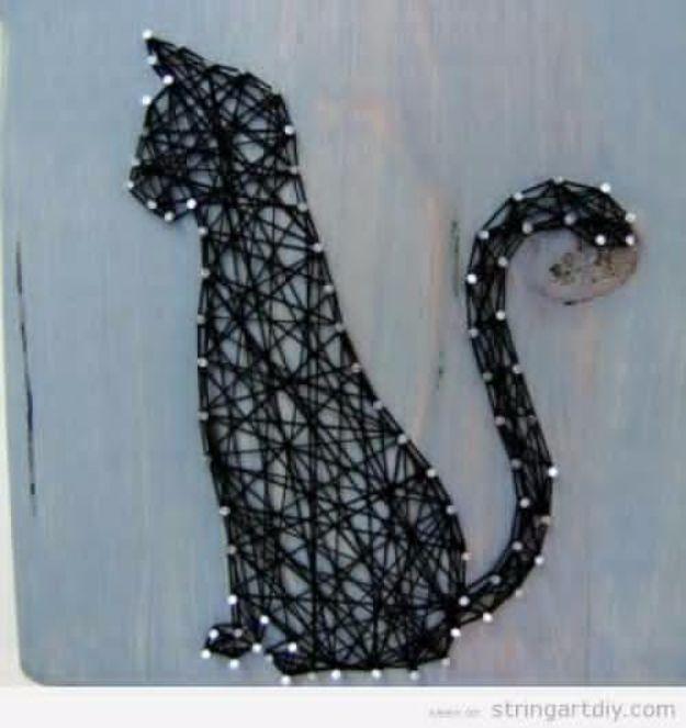 Cat string art DIY, a black thread cat with a curled spiral tail outlined in nails on a weathered blue wooden board