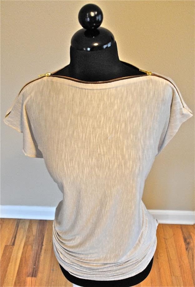 Beige jersey top on a black dress form with a gold zipper running across both shoulders in place of the neckline seam
