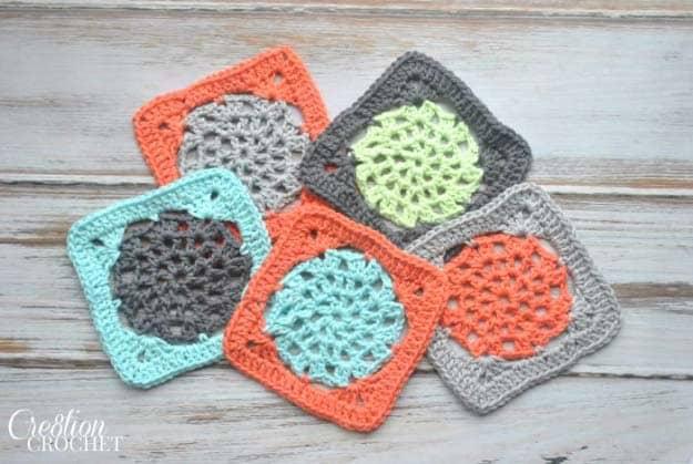 Lace square crochet, crochet squares in orange, gray, green and aqua with open lace centers laid out on weathered white wood