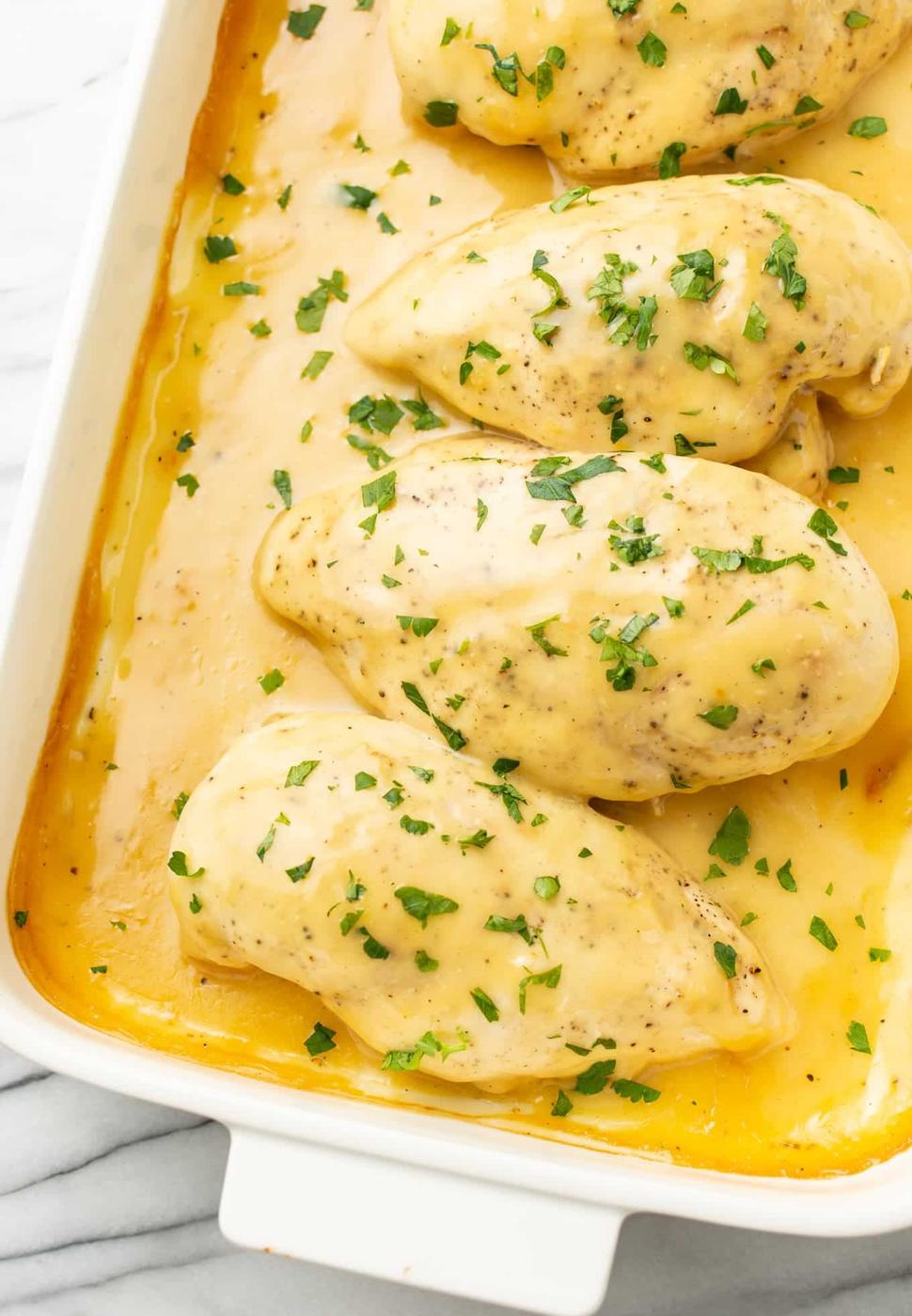 Baked honey mustard chicken, four chicken breasts in golden honey mustard sauce in a white baking dish