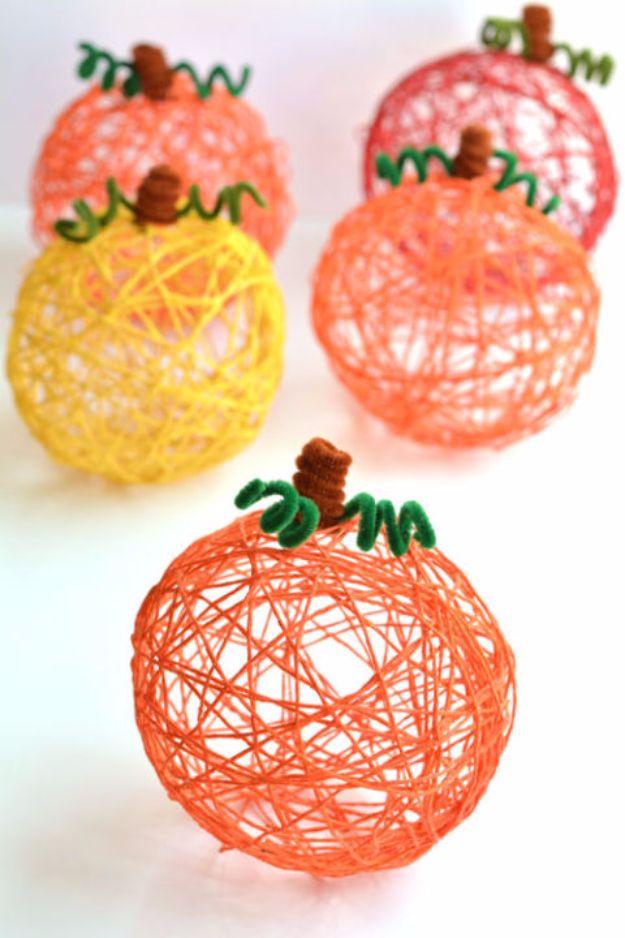 Yarn pumpkins in orange, yellow, red and pink made over balloons, with brown and green pipe cleaner stems