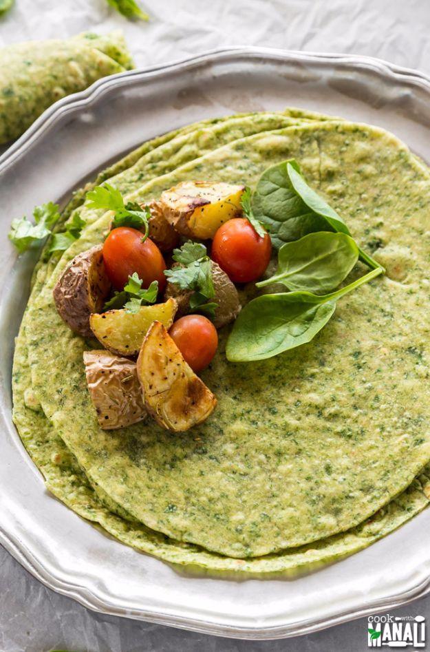 Green homemade spinach tortilla on a silver plate topped with roast potatoes, cherry tomatoes and spinach